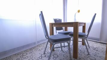 Een kamer met een houten tafel, vier stoelen, een vaas met een enkele bloem en een kamerbreed tapijt.