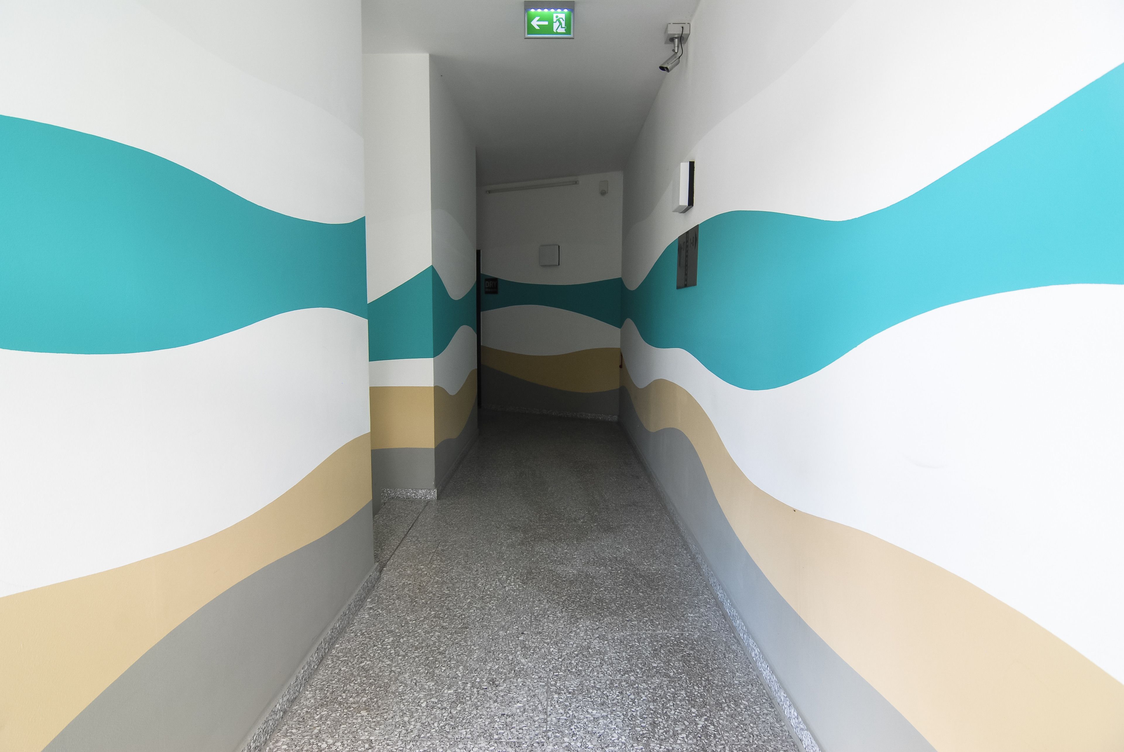 A hallway with wavy wall designs and a tiled floor.