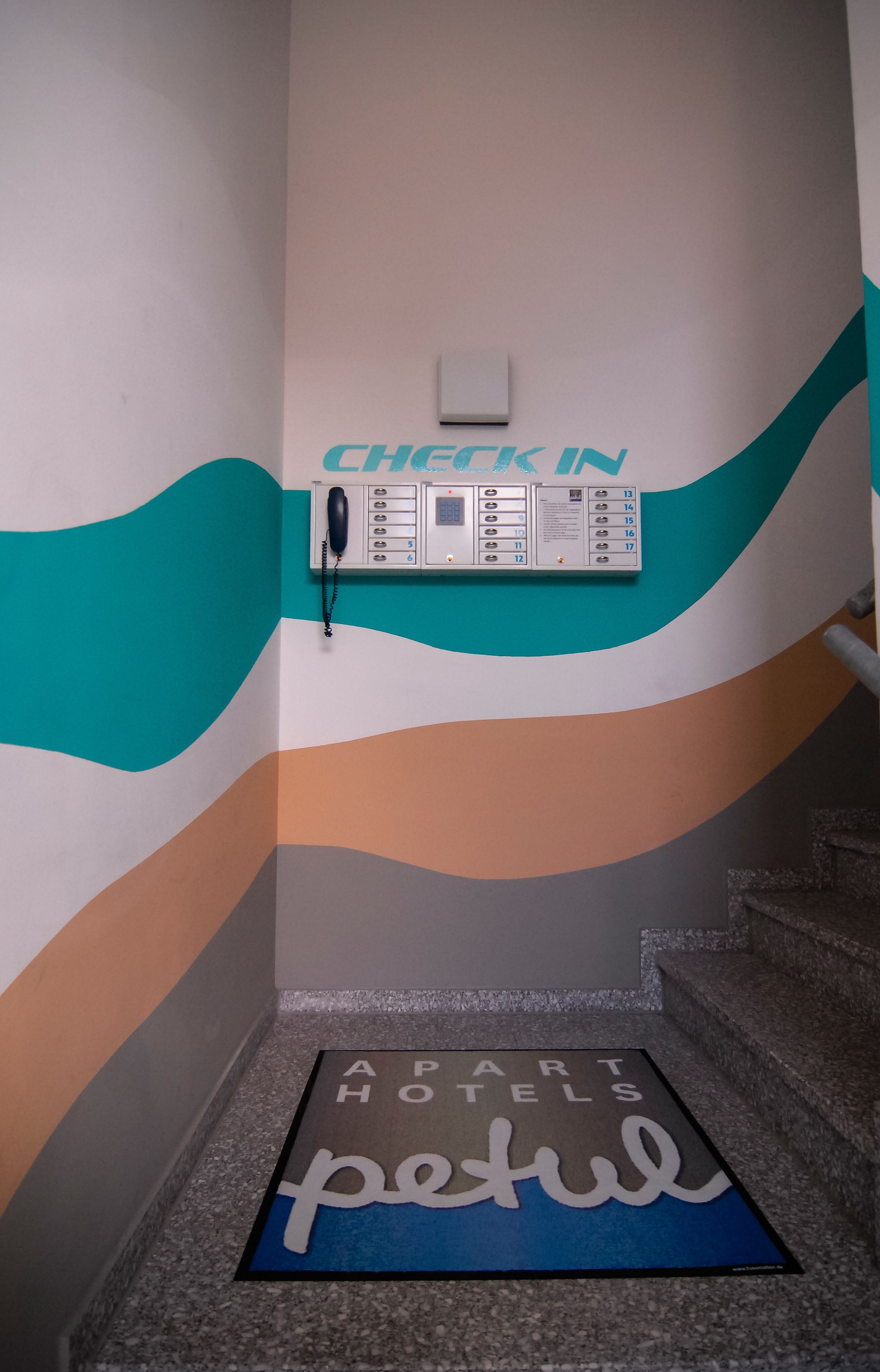 A hotel reception area with a check-in counter, a phone, and a digital display.