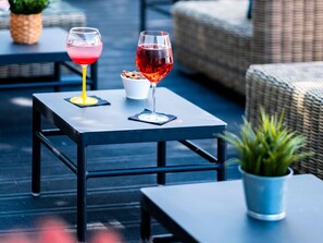 A table with two glasses of red wine, a pineapple, and a small bowl of snacks. - ibis Styles Quiberon Centre (Quiberon)