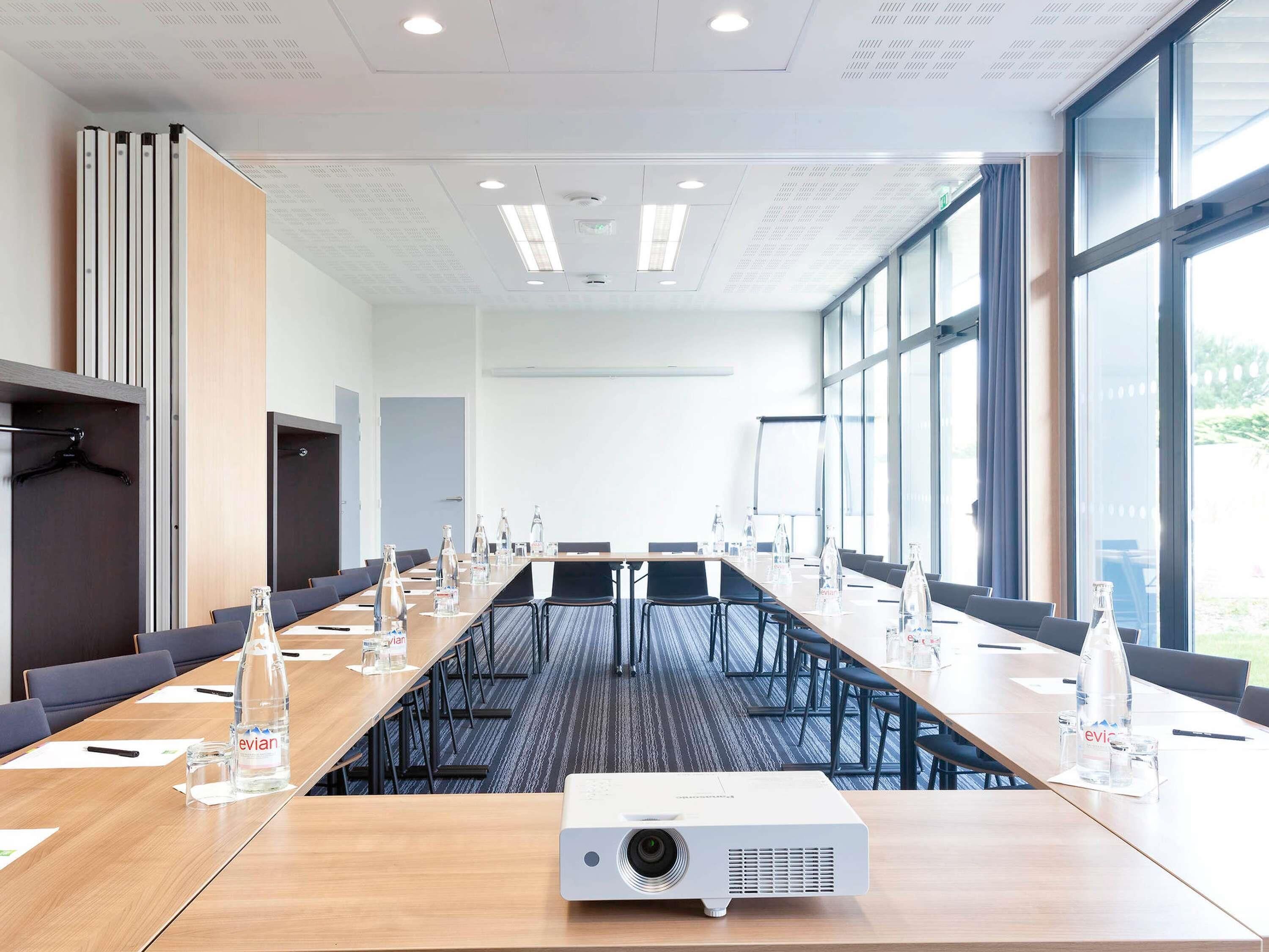 A conference room with a long table, chairs, a projector, and water bottles.