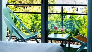 A balcony with a bed, two chairs, and two glasses of red wine on a small table. - ibis Styles Quiberon Centre (Quiberon)