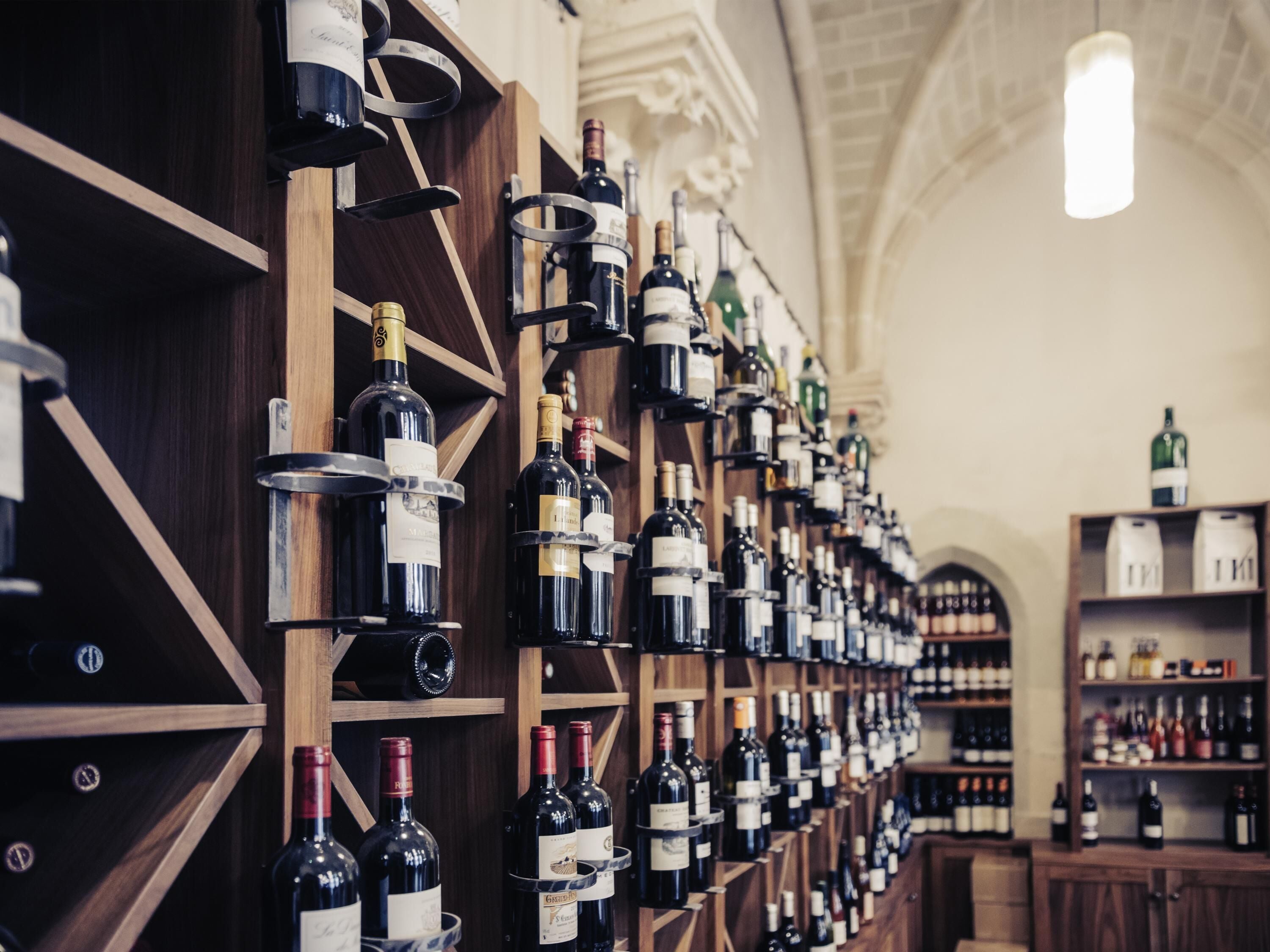 A wine cellar with numerous wine bottles organized on wooden shelves.