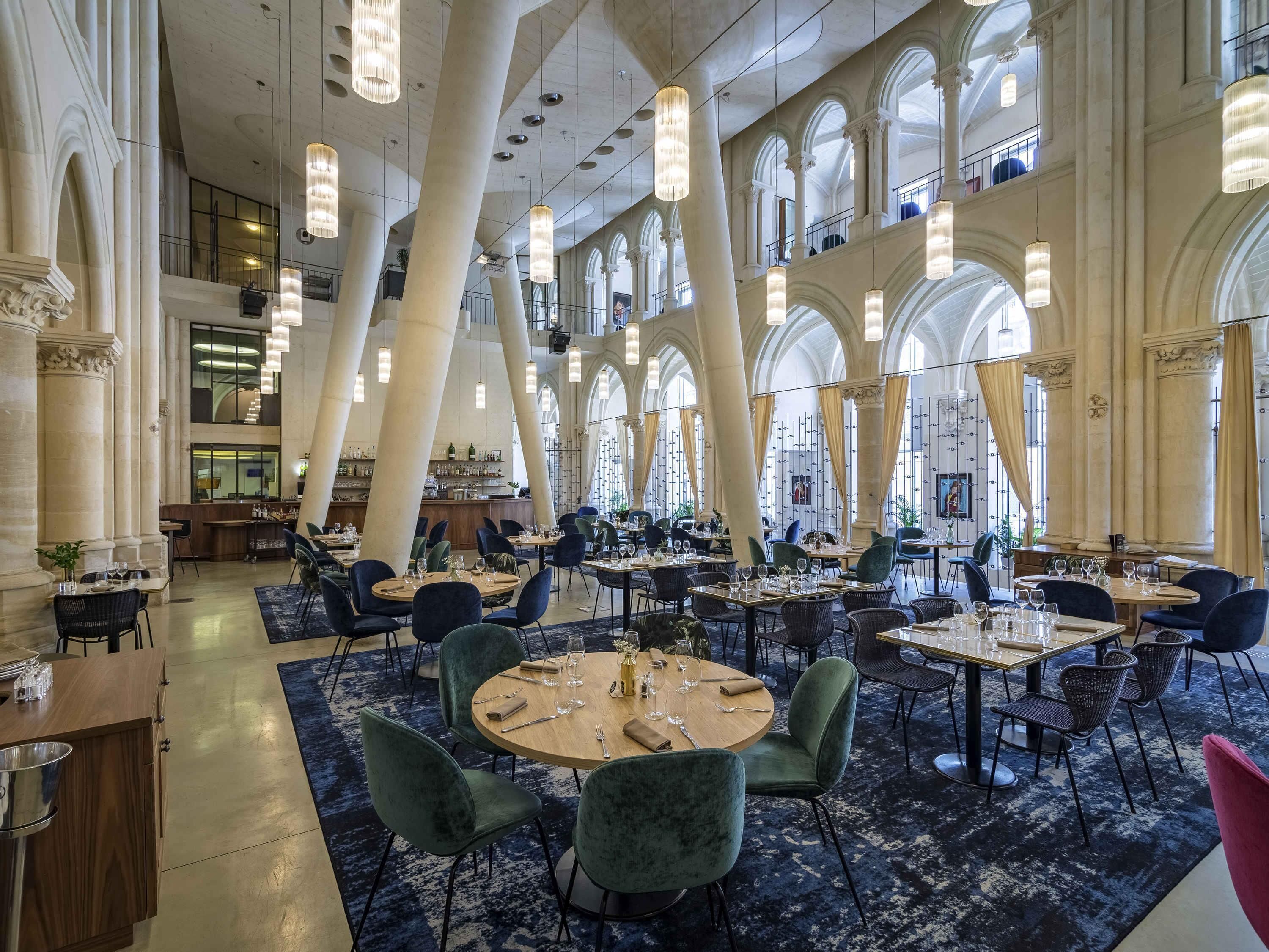 A spacious dining area with high ceilings, large windows, and modern chandeliers.