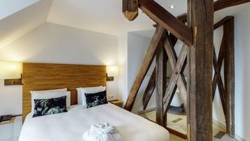 A hotel room with a wooden ceiling structure, a bed with white bedding, and two wall-mounted lamps.
