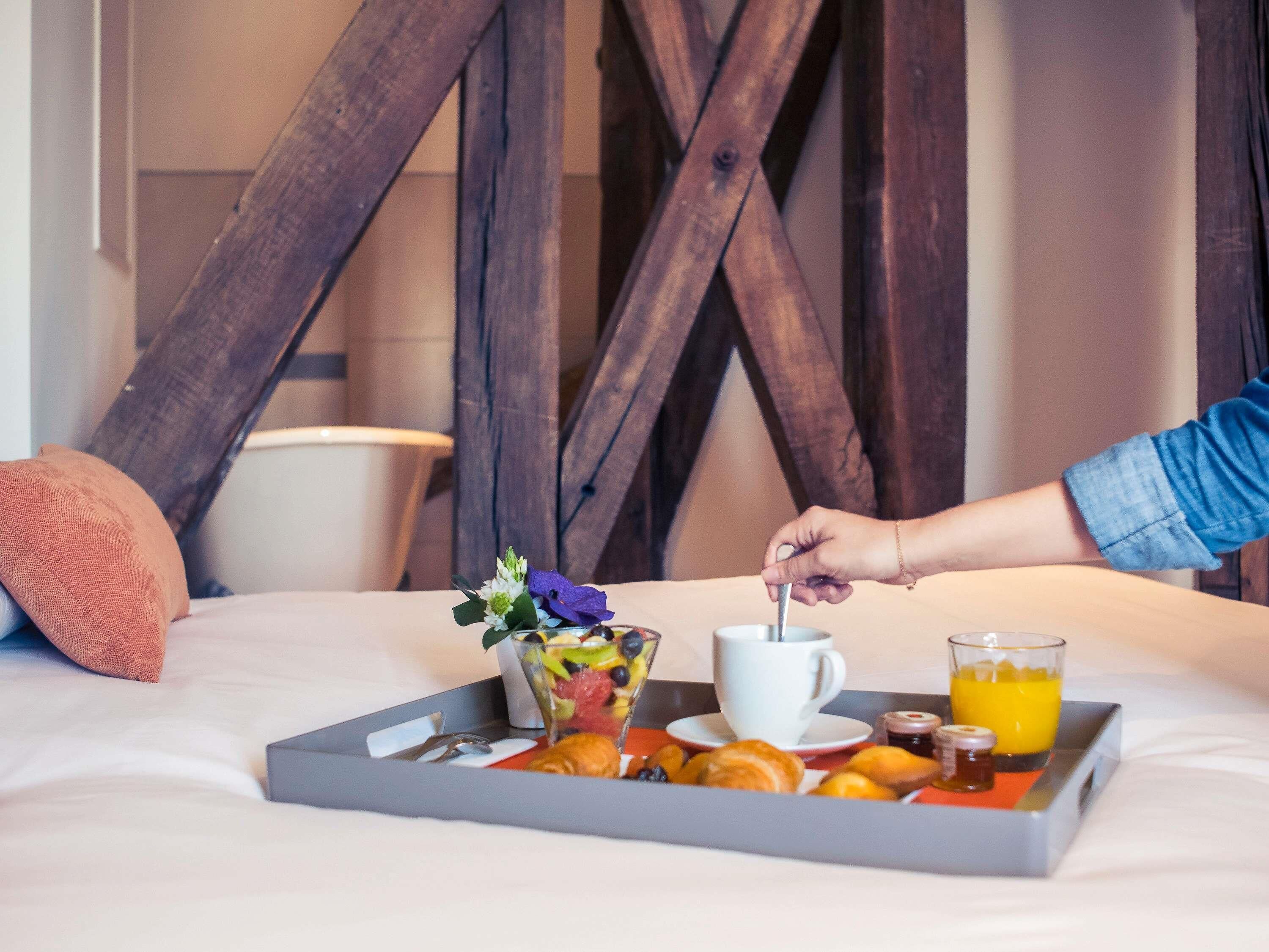 A breakfast tray on a bed with a cup, juice, and pastries.