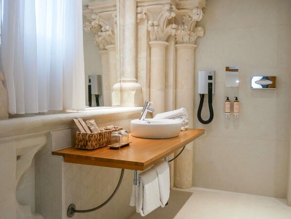 A bathroom with a wooden vanity, a sink, a towel rack, and a mirror.