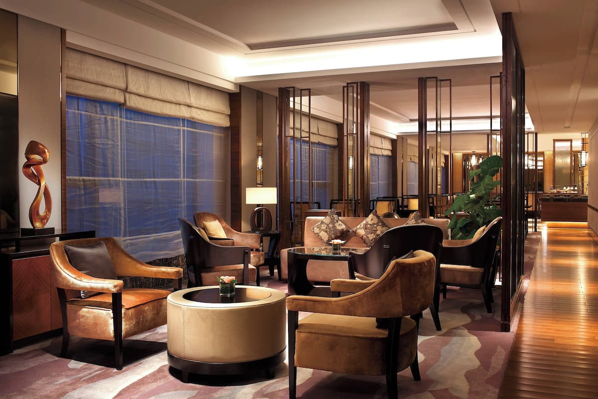 A spacious lobby with leather armchairs, a round coffee table, and a large plant.