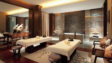 Relax in a serene spa room with two massage tables, a large mirror, and a desk.