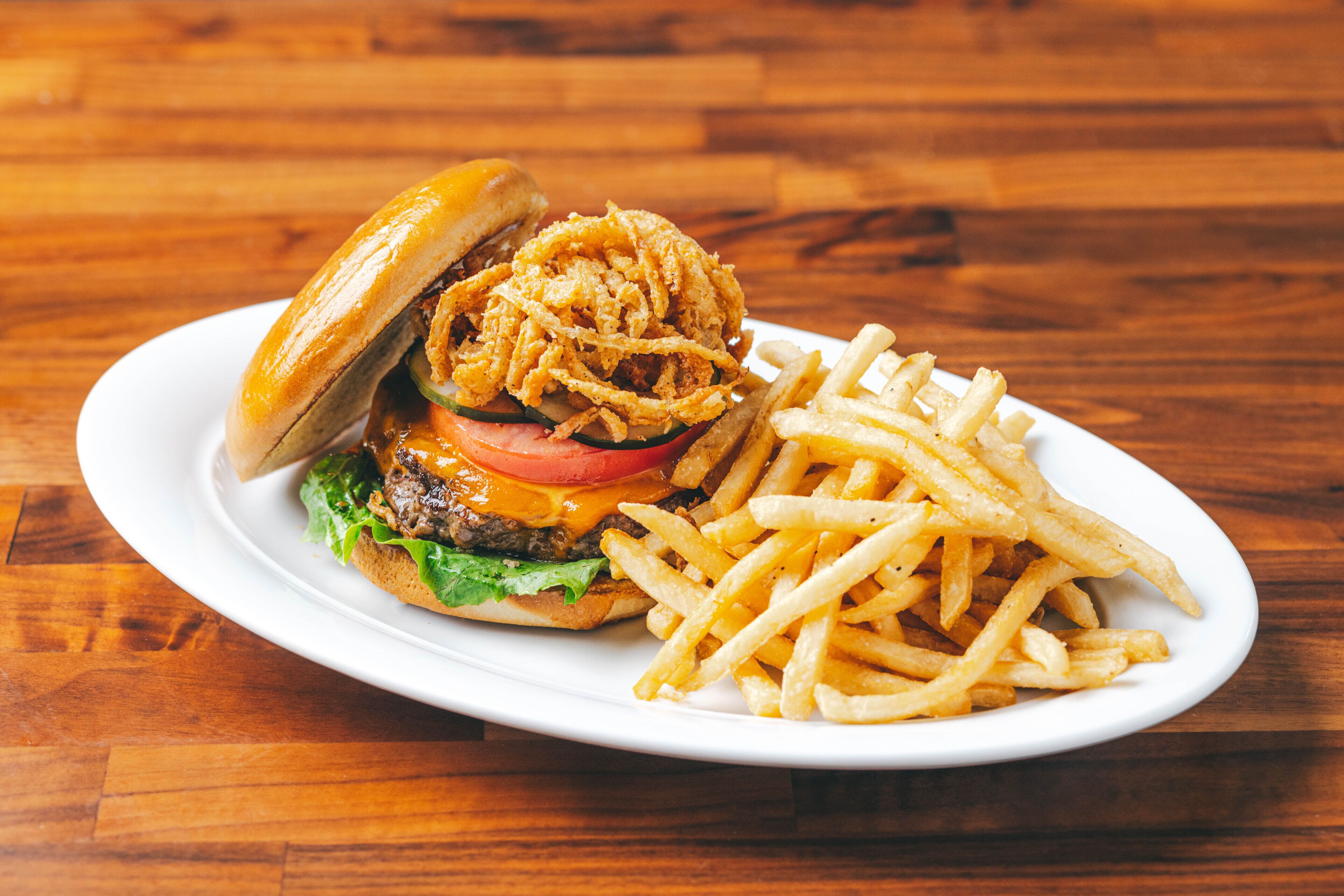 Une assiette avec un hamburger et des frites, posée sur une table en bois.
