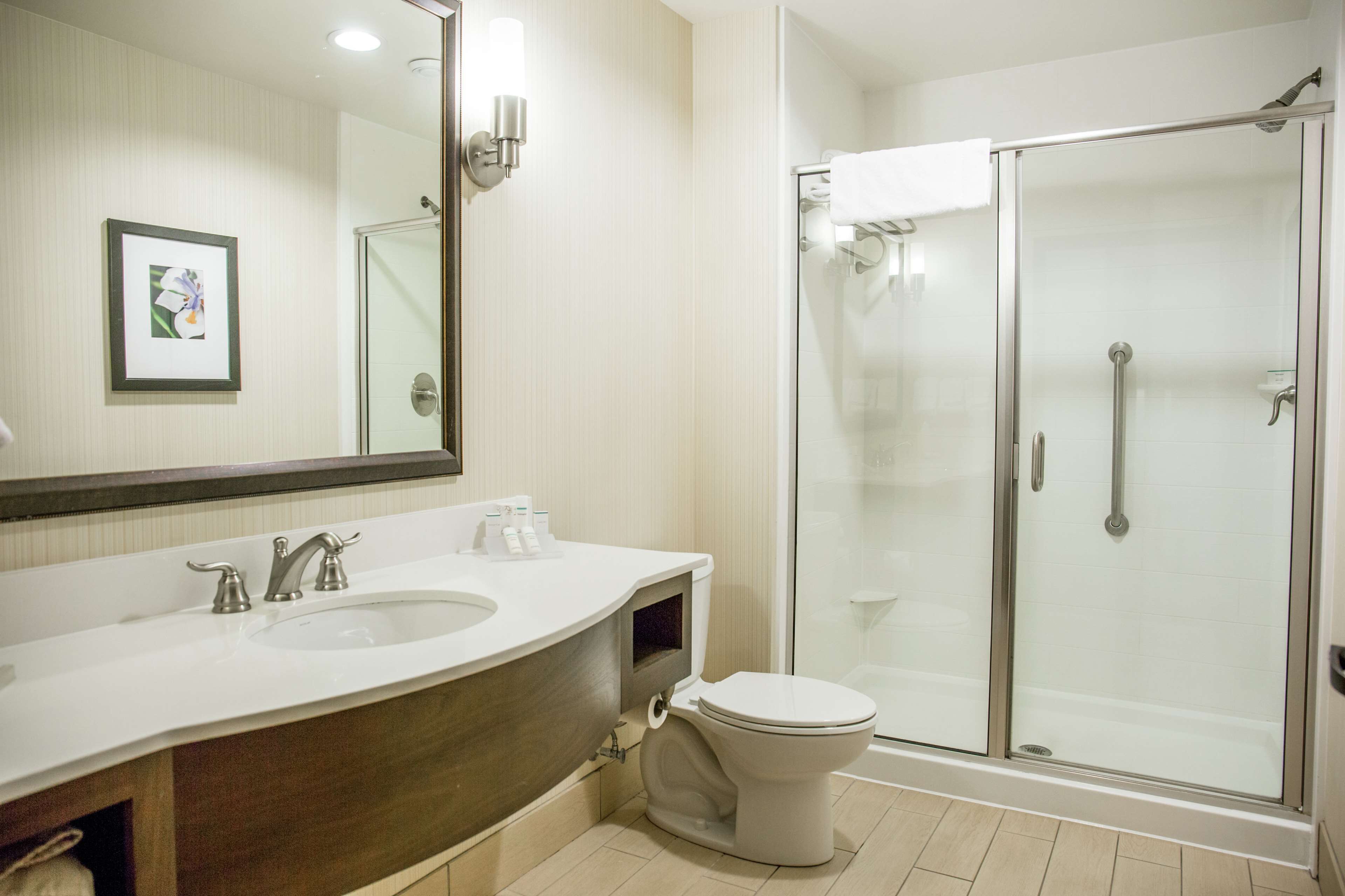 Une salle de bain moderne avec un grand miroir, un lavabo, des toilettes et une douche à parois de verre.