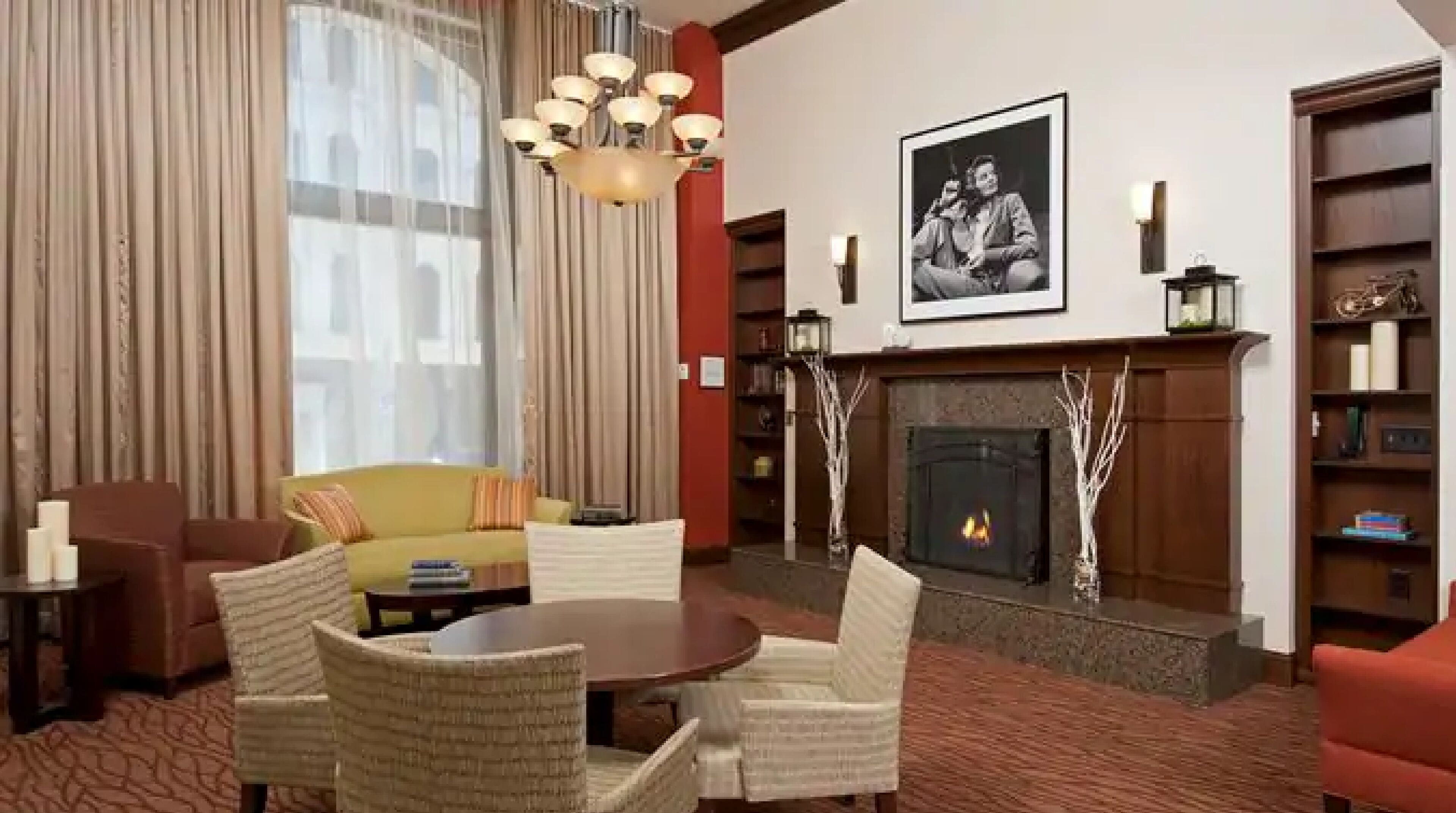 Een woonkamer met een open haard, een bank, een eettafel en een boekenkast.