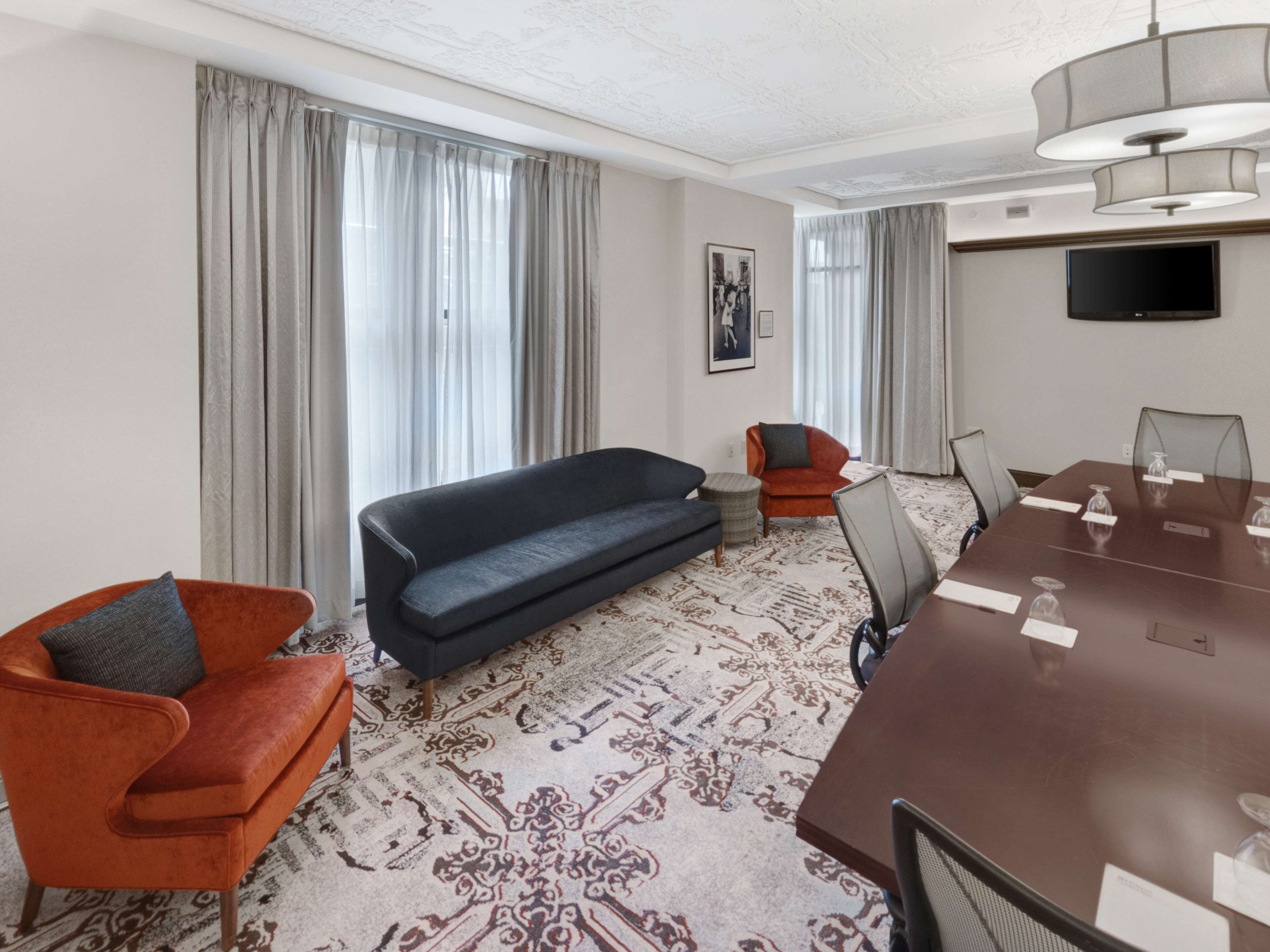 Ein Hotelzimmer mit einer Couch, einem Sessel und einem Konferenztisch mit Stühlen.