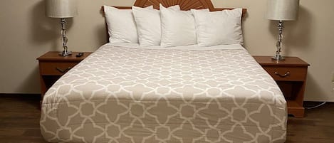A neatly made bed with a patterned bedspread, two bedside lamps, and a framed picture on the wall above.