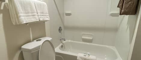 A bathroom with a toilet, a bathtub, and a shower. There are towels hanging on the wall.