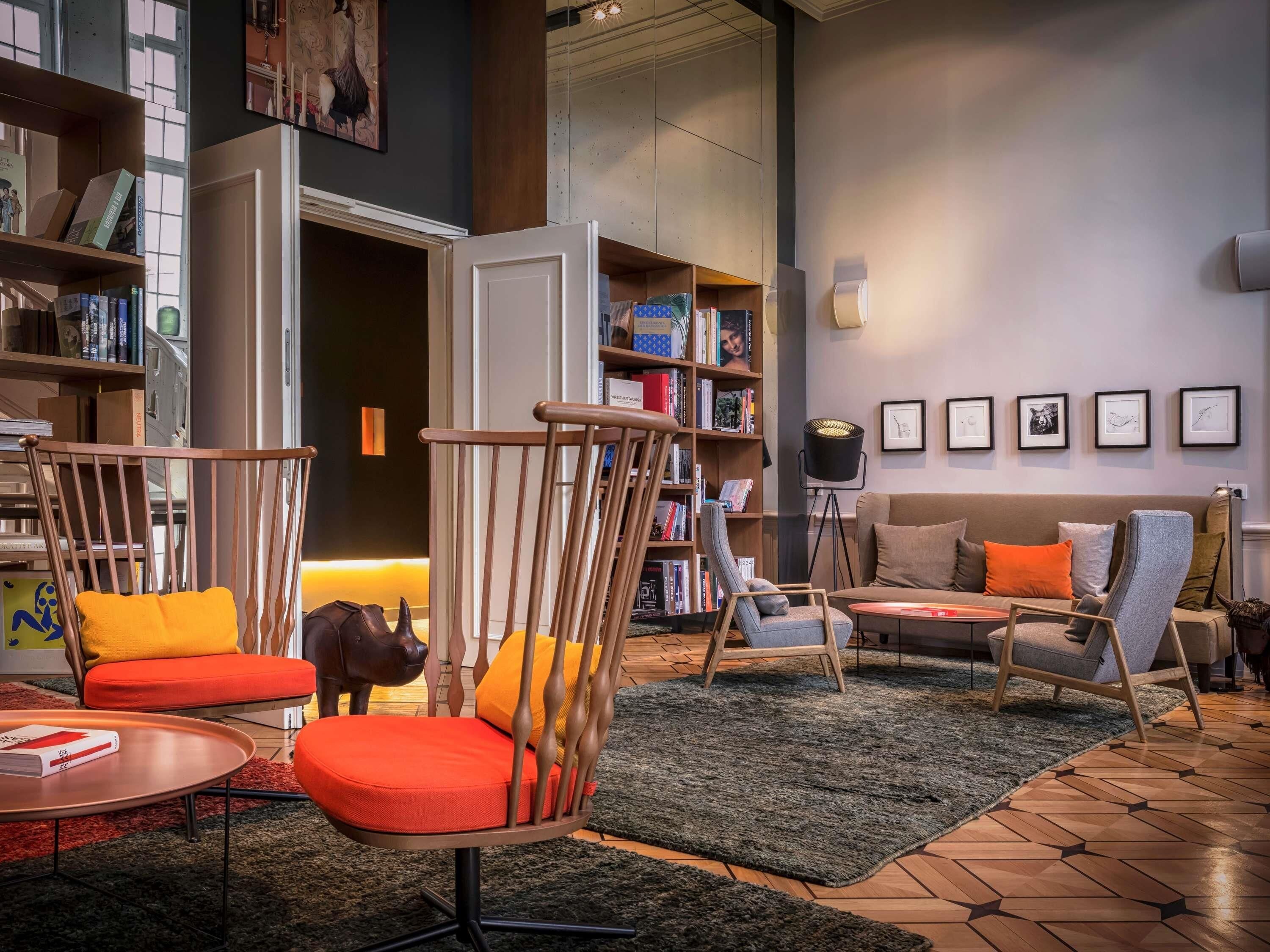 A modern living room with a wooden chair, a sofa, and a bookshelf filled with books.