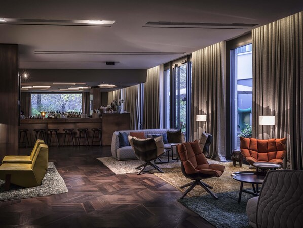 A modern hotel lobby with a bar area, seating arrangements, and large windows providing natural light. - Das Stue (Berlin)