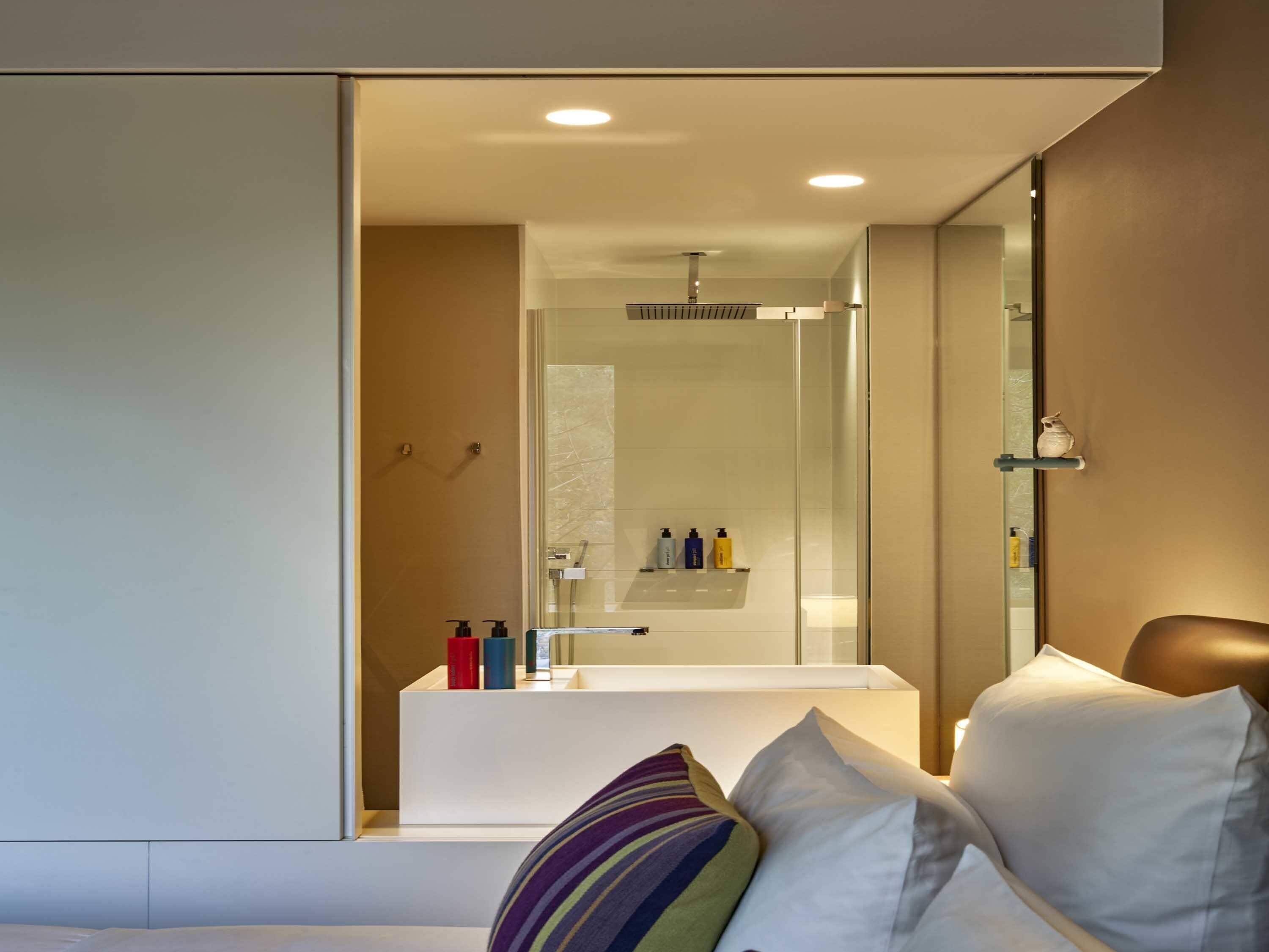 A modern bathroom with a glass shower enclosure, a white bathtub, and toiletries on a shelf.