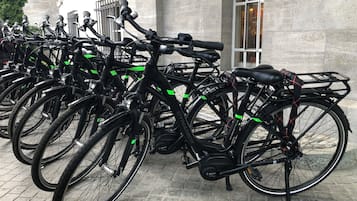A row of stationary bicycles parked in front of a building with a stone facade and a window.