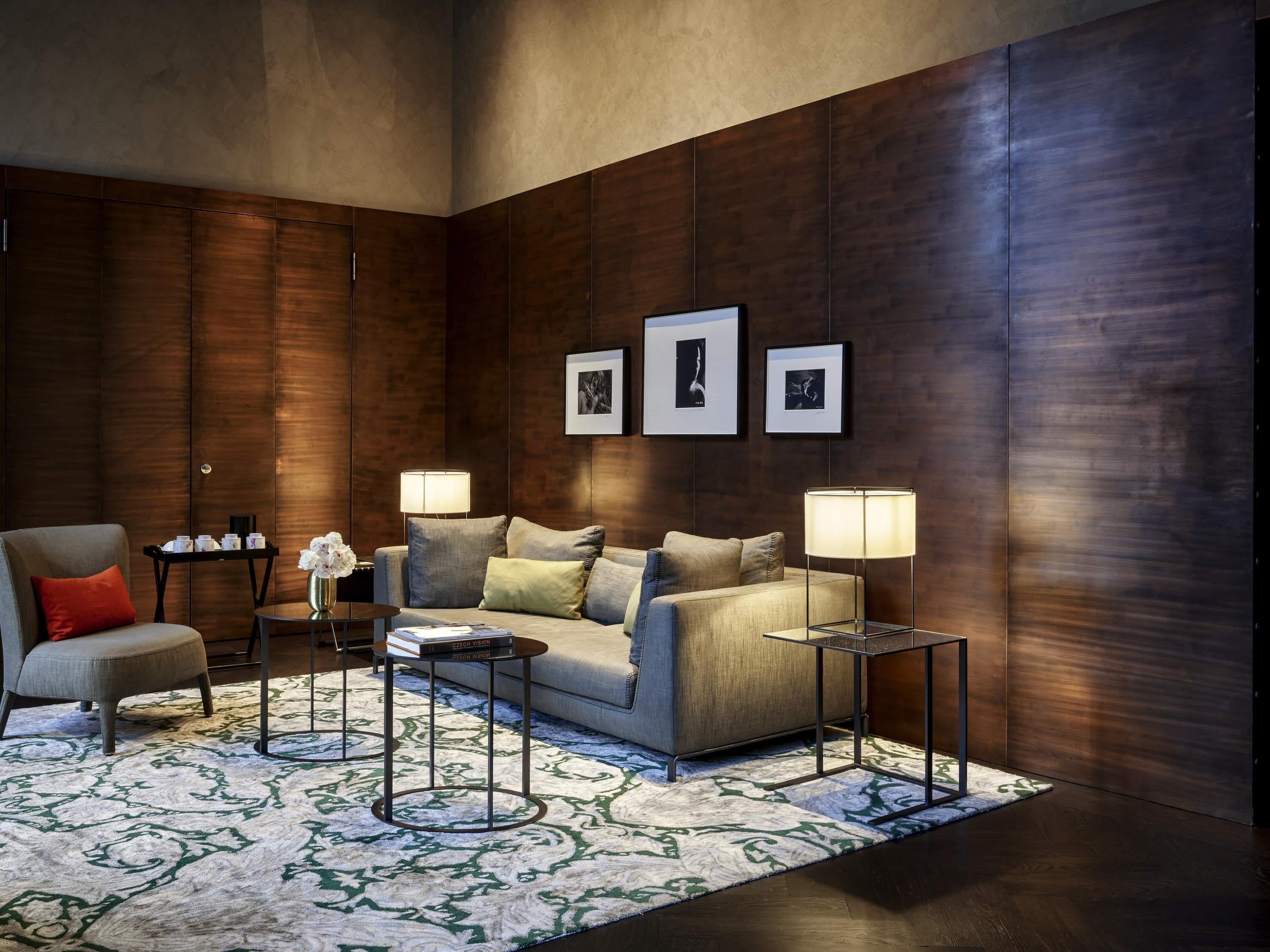A modern living room with a sofa, two side tables, a coffee table, and a patterned rug.