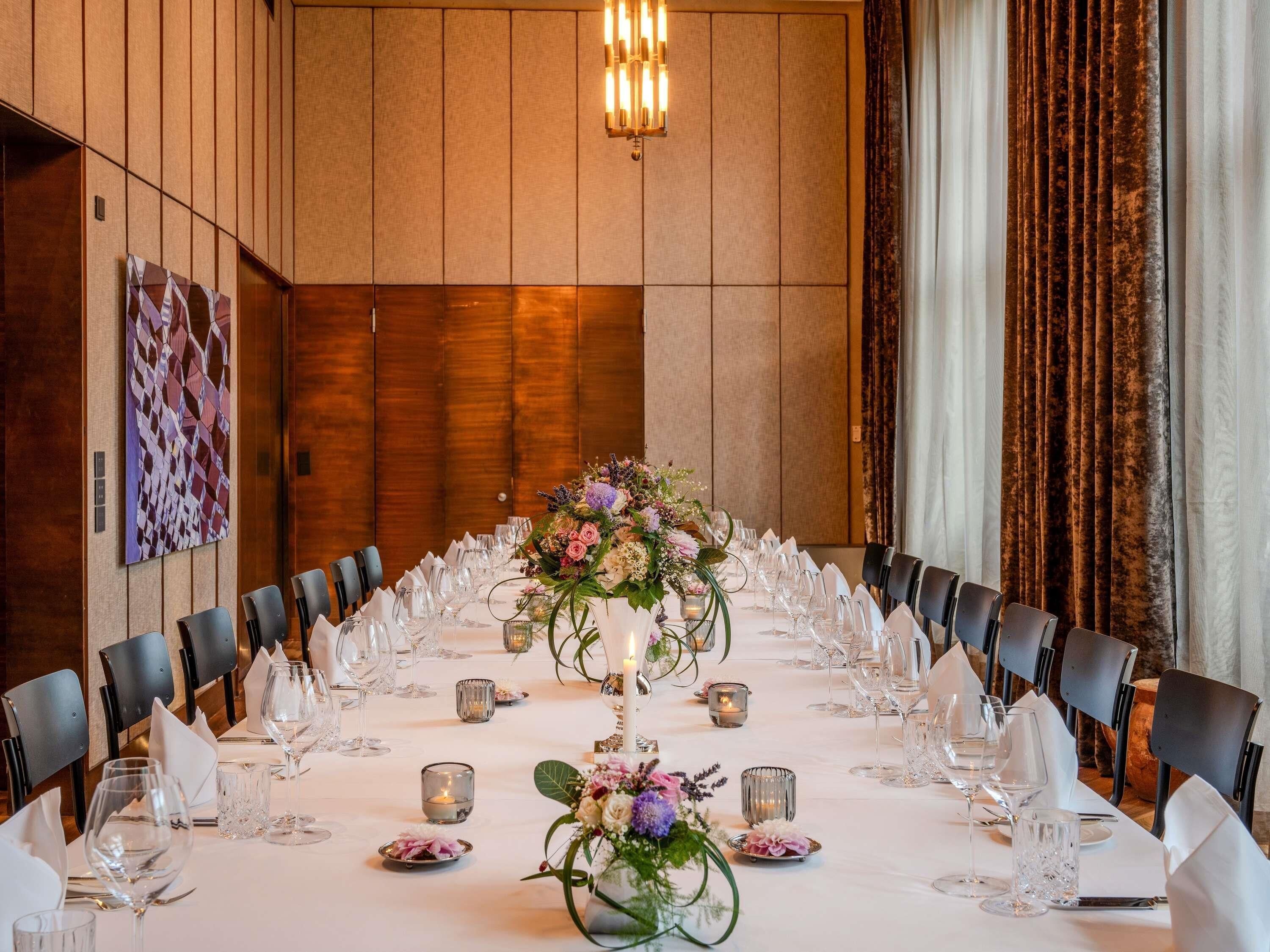 A long dining table set with chairs, candles, and floral centerpieces.