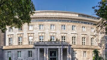 A large, historic building with a curved facade, multiple windows, and a prominent entrance with columns.