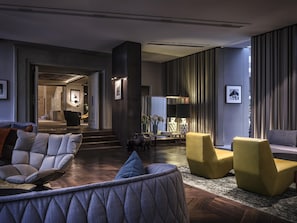 A modern lobby with a sofa, armchairs, a coffee table, and a staircase leading to another area. - Hotel Das Stue Berlin (Berlin)