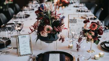 A dining table set with plates, cutlery, glasses, and floral centerpieces.