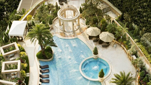A large, multi-level swimming pool with various seating areas and surrounding greenery. - The Langham, Shenzhen (Shenzhen)