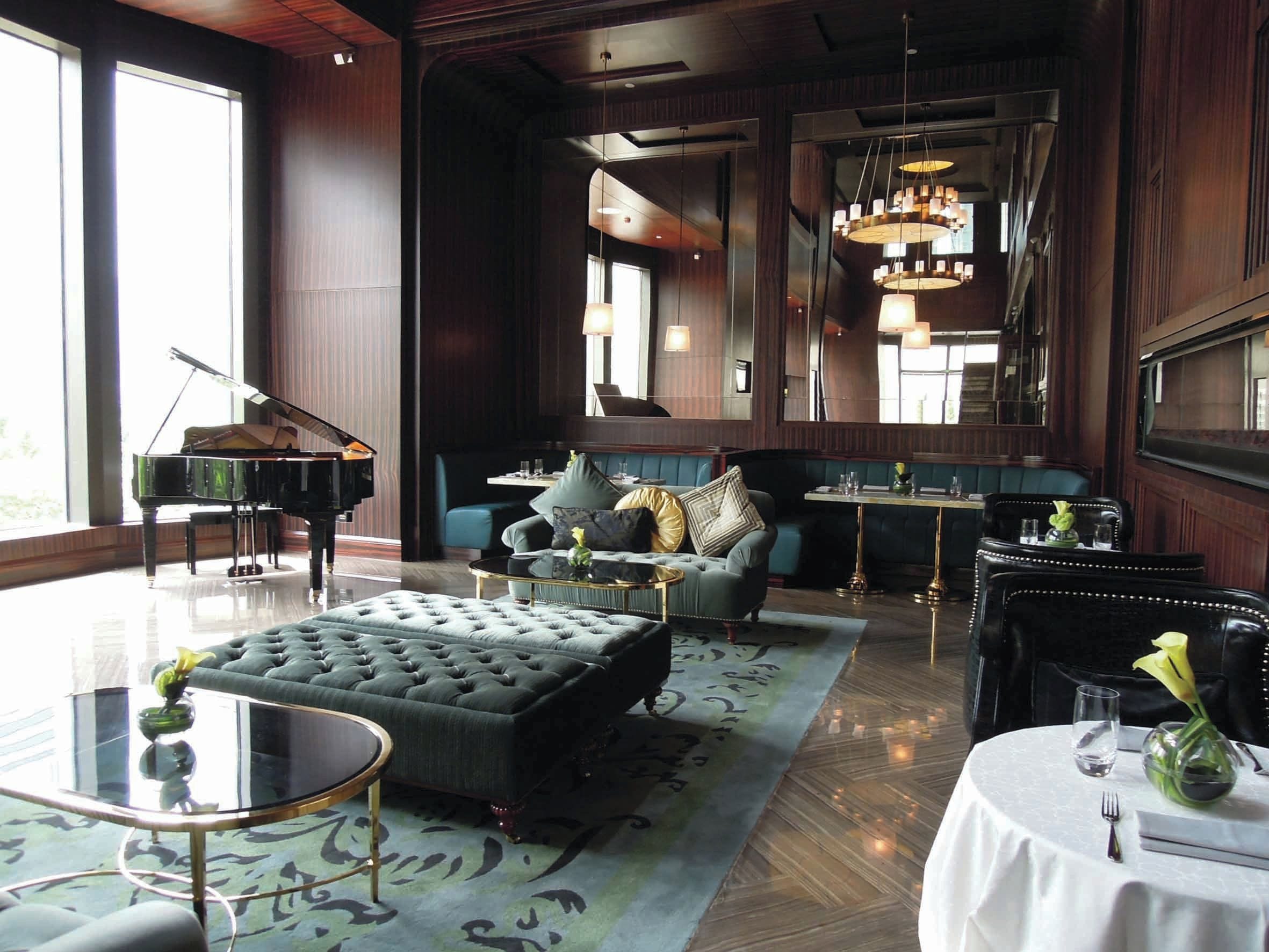 A spacious lounge area with a grand piano, comfortable seating, and a large mirror reflecting the room.