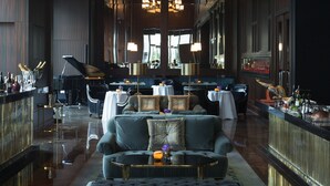 A spacious lobby with a grand piano, a bar area, and a seating arrangement with a large sofa and ottoman. - The Langham, Shenzhen (Shenzhen)