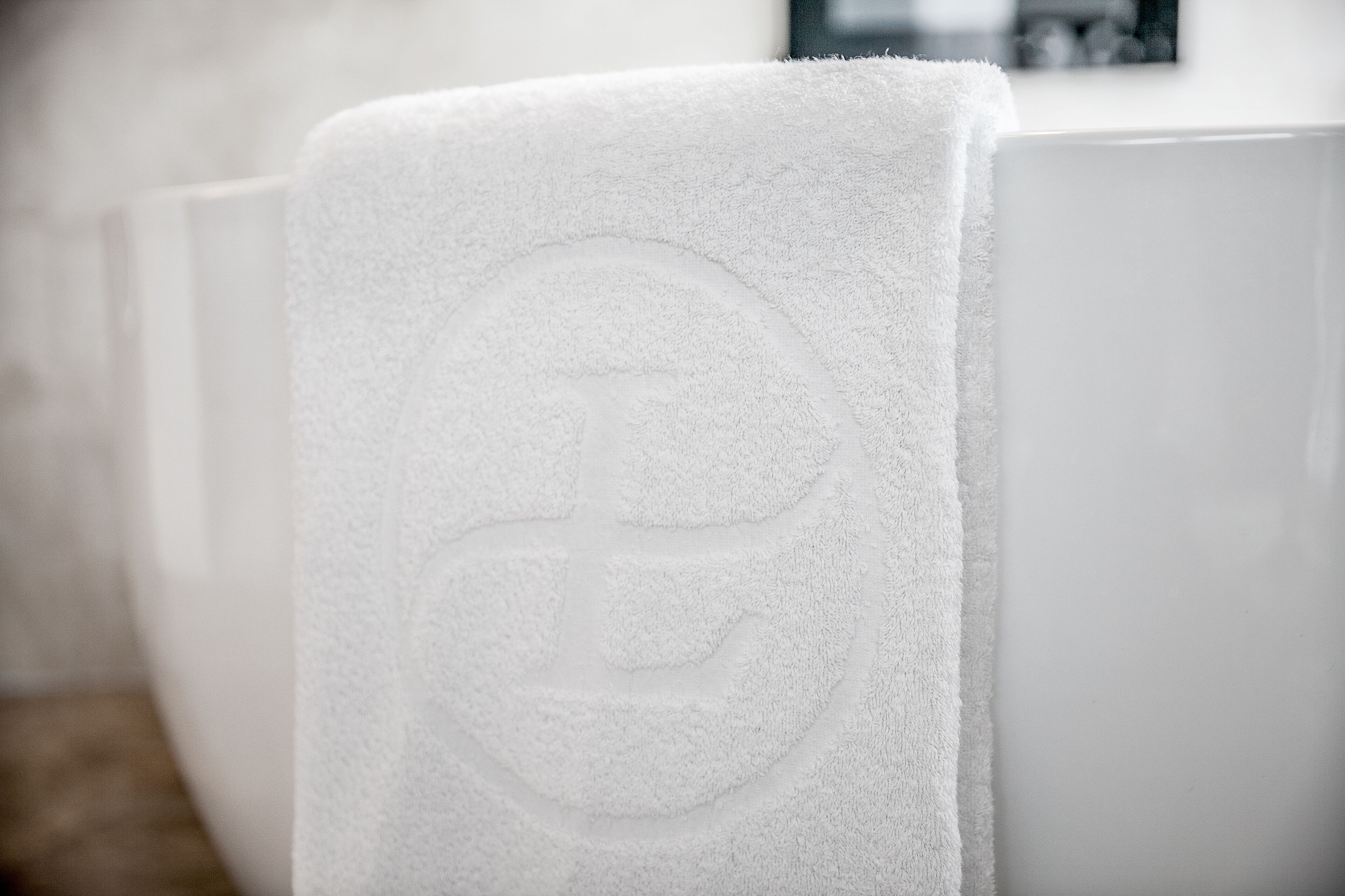 Una toalla blanca con un logo sobre una bañera blanca.