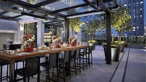 An outdoor dining area with a long table set for a meal, surrounded by chairs, and featuring decorative elements like flowers and birdcages. - The Langham, Shenzhen (Shenzhen)