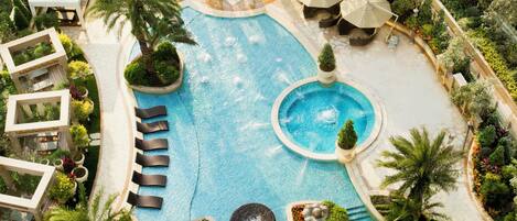 A large outdoor swimming pool with multiple seating areas and surrounding greenery.