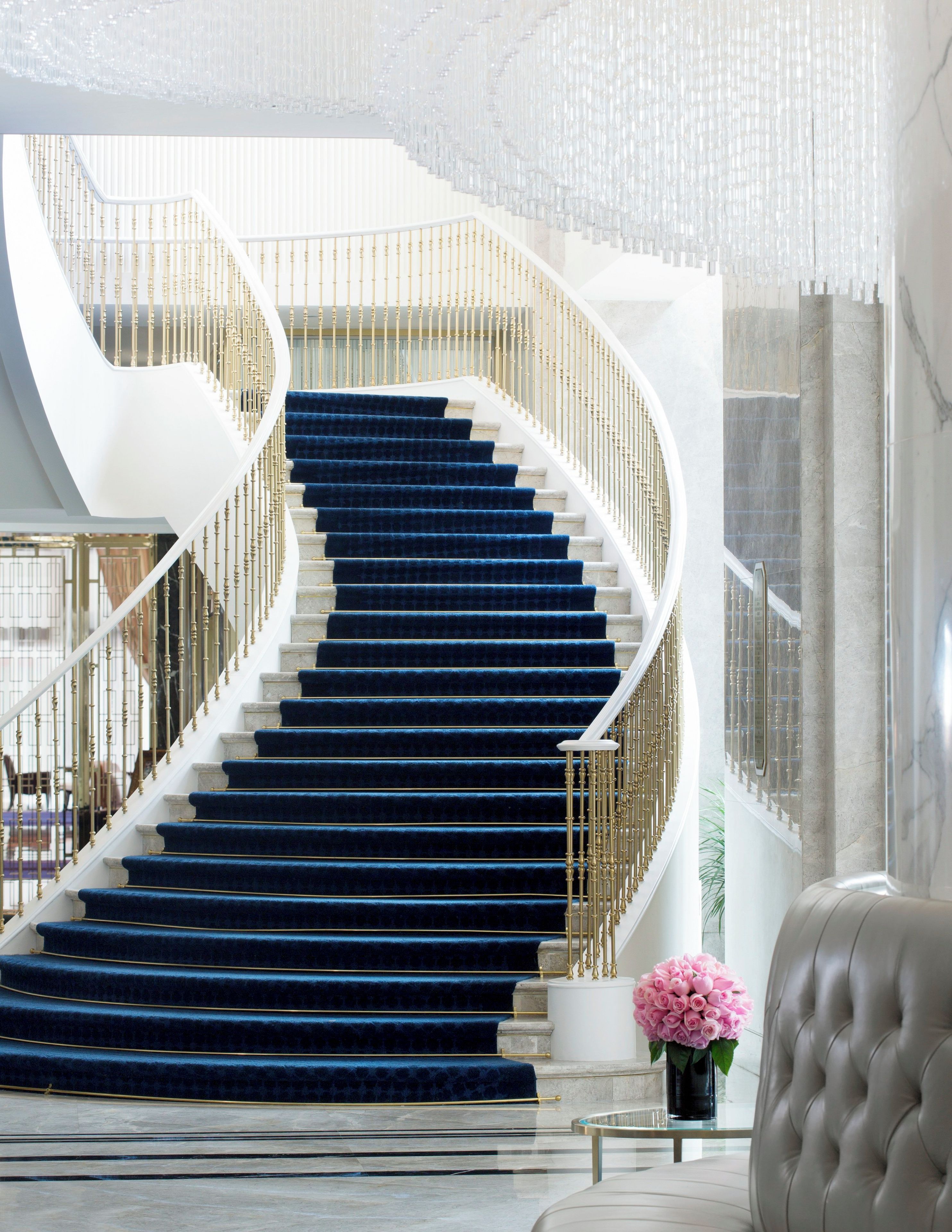A spiral staircase with blue carpet and gold railings in a modern interior.
