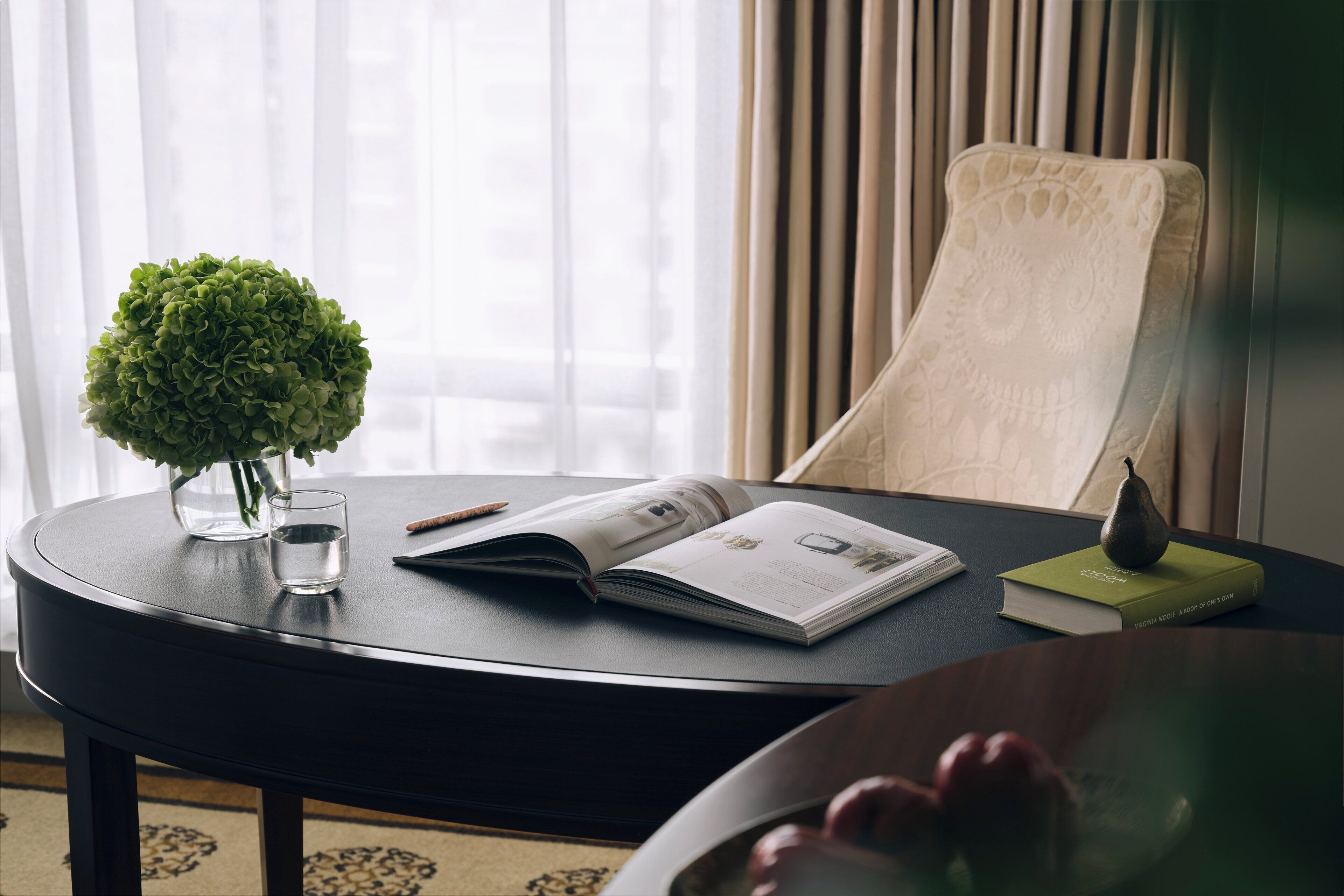 A round table with a book, a glass of water, and a small potted plant.