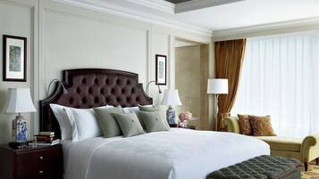 Habitación de hotel con una cama grande, dos mesitas de noche con lámparas, una silla, un sofá y un adorno en la pared.