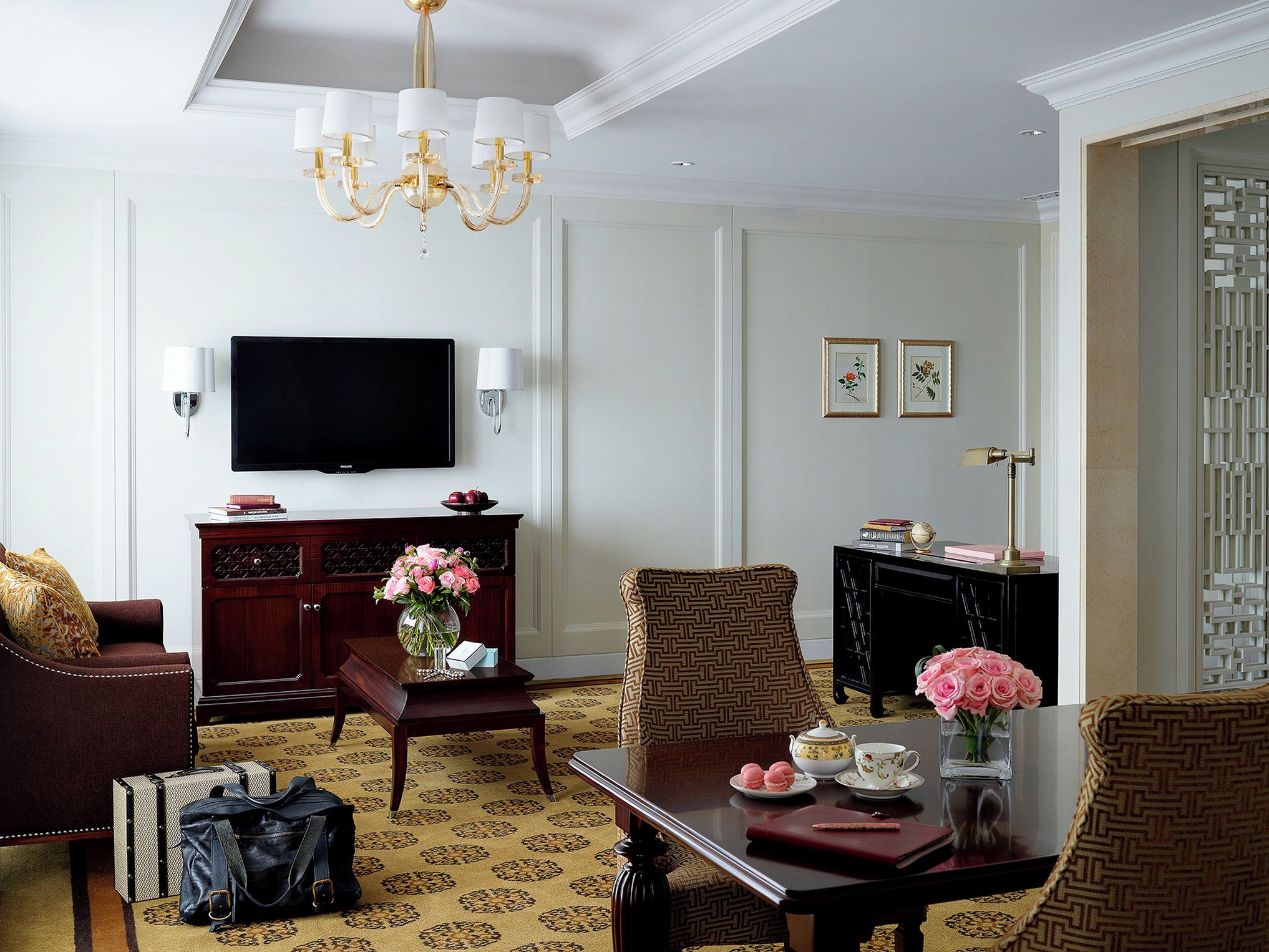 A well-appointed living room with a television, a chandelier, a fireplace, and a dining area with a table and chairs.