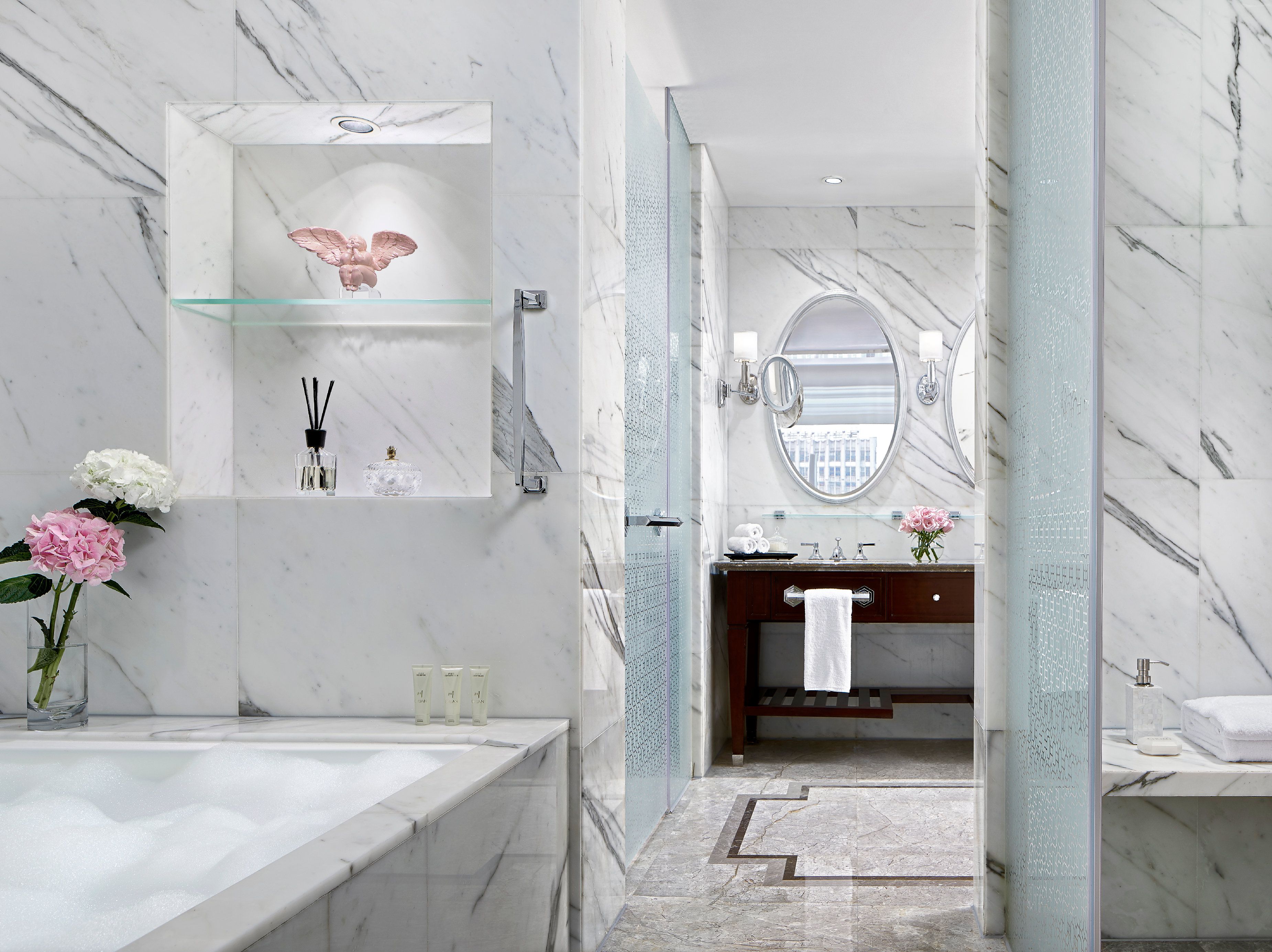 Un baño moderno con un lavamanos de mármol, cabina de ducha de vidrio y tocador con espejo.