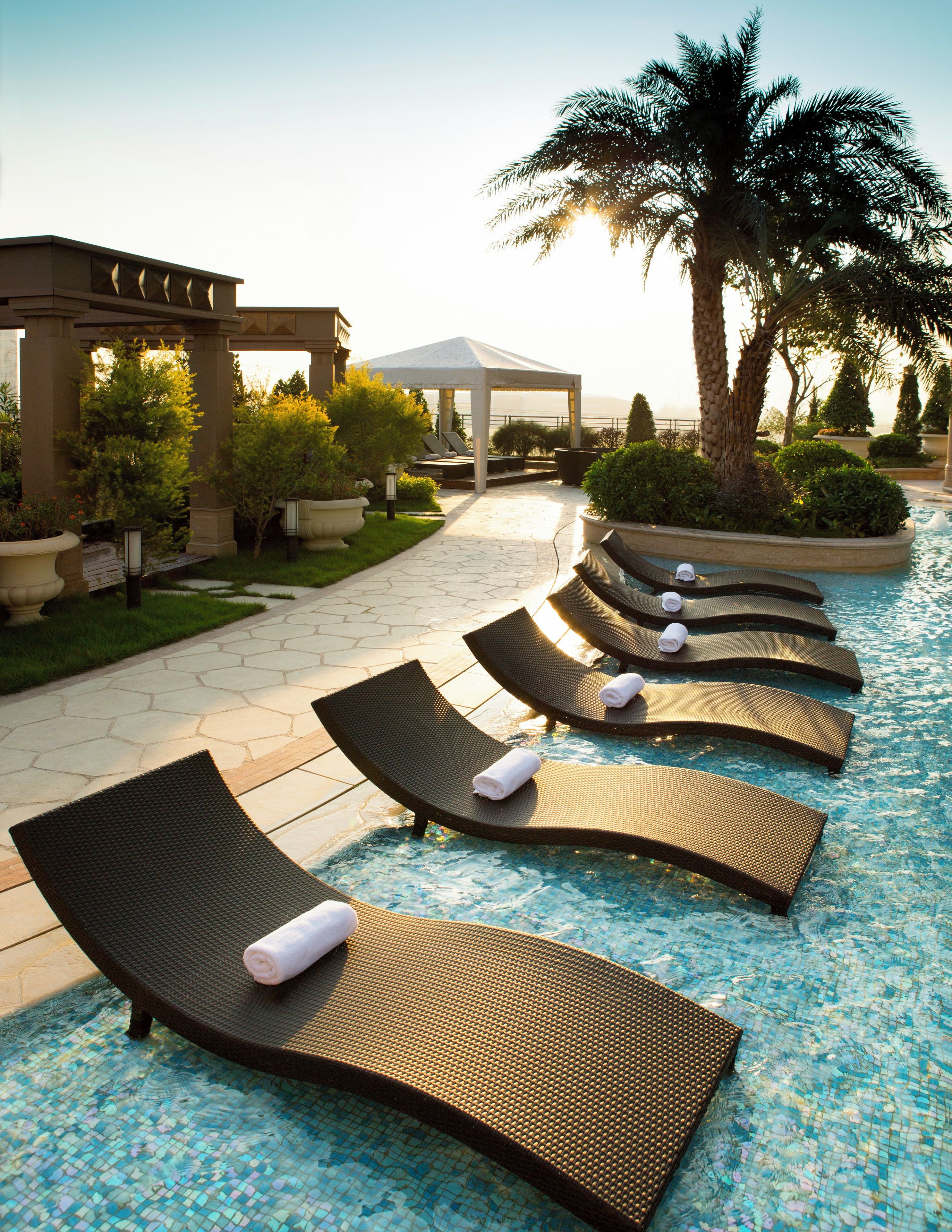 A poolside area with lounge chairs and a covered seating area.