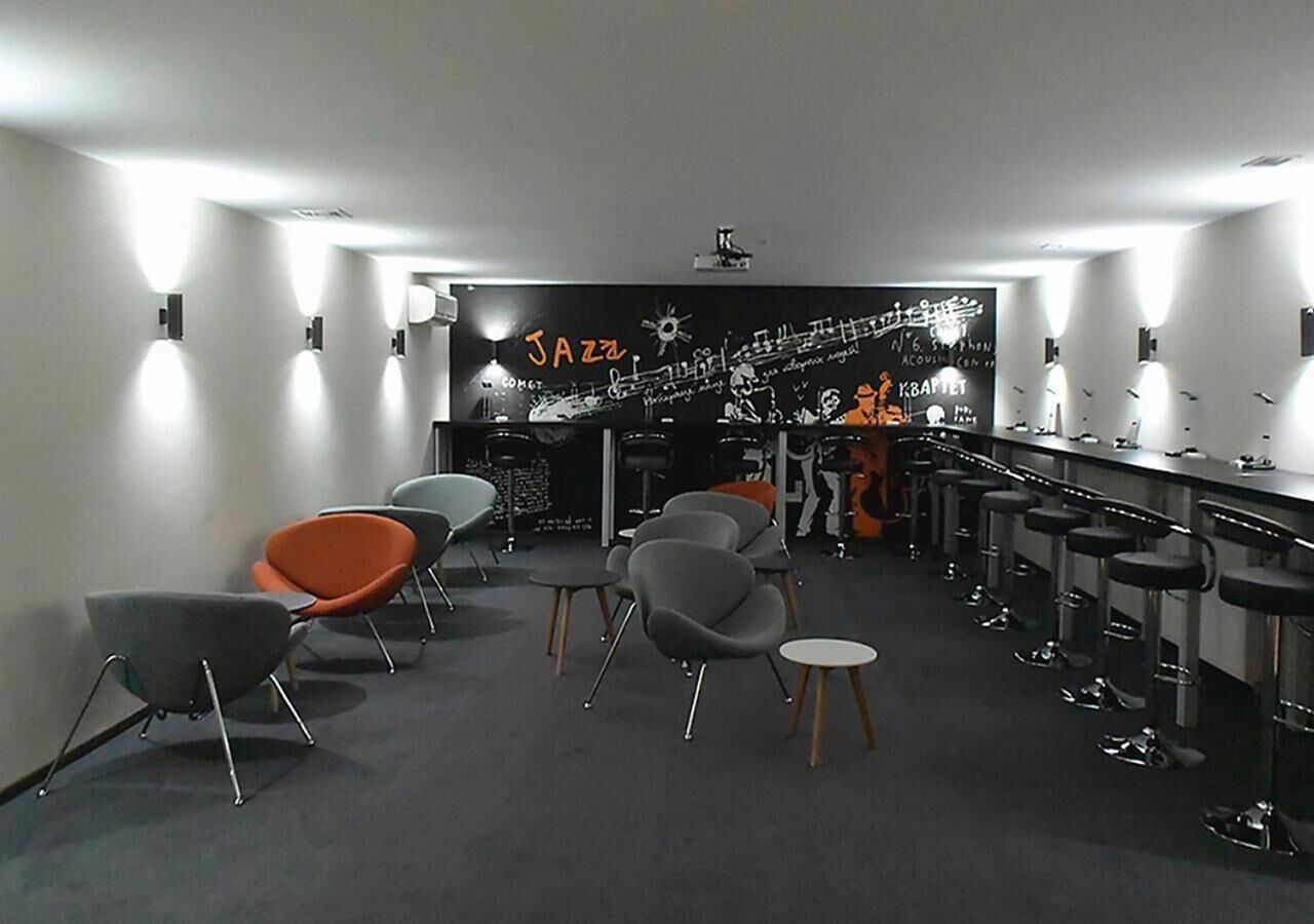 A modern bar area with a black and white mural, several bar stools, and a few chairs.