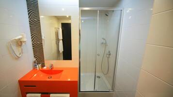 Un baño moderno con ducha envuelta en vidrio, un lavabo rojo y un espejo con estampado de cebra.