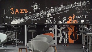 Un bar à thème jazz, doté de chaises modernes et d'un mur noir où sont dessinées des portées et des instruments de musique.