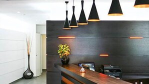 Un espace bar moderne avec un comptoir en bois, des tabourets de bar noirs et des luminaires suspendus.