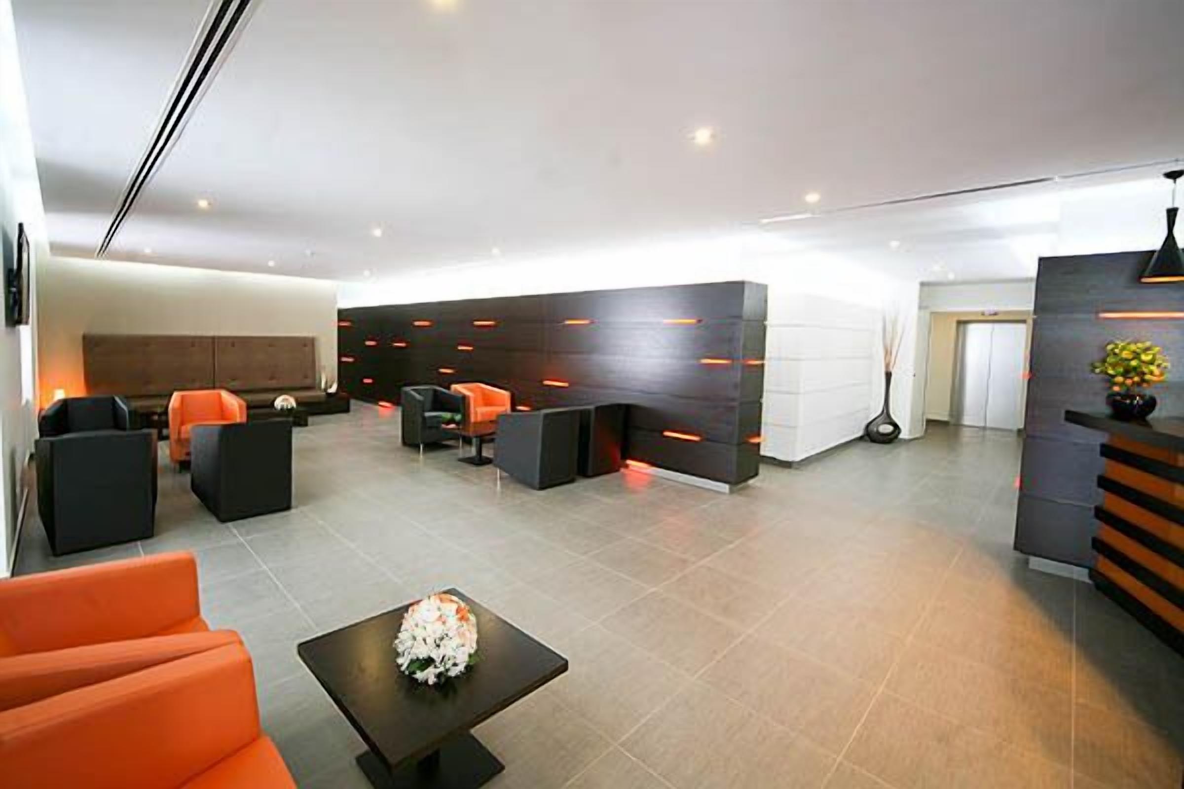 A modern lobby with a reception desk, seating area, and a large wall with integrated lighting.