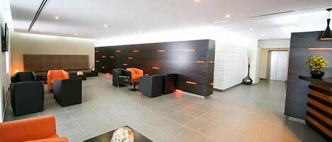 A modern lobby with a reception desk, seating area, and a large wall with integrated lighting.