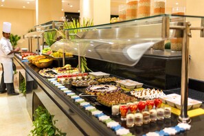 A buffet with various food items and a chef in the background. - Concorde Moreen Beach Resort & Spa (Marsa Alam)