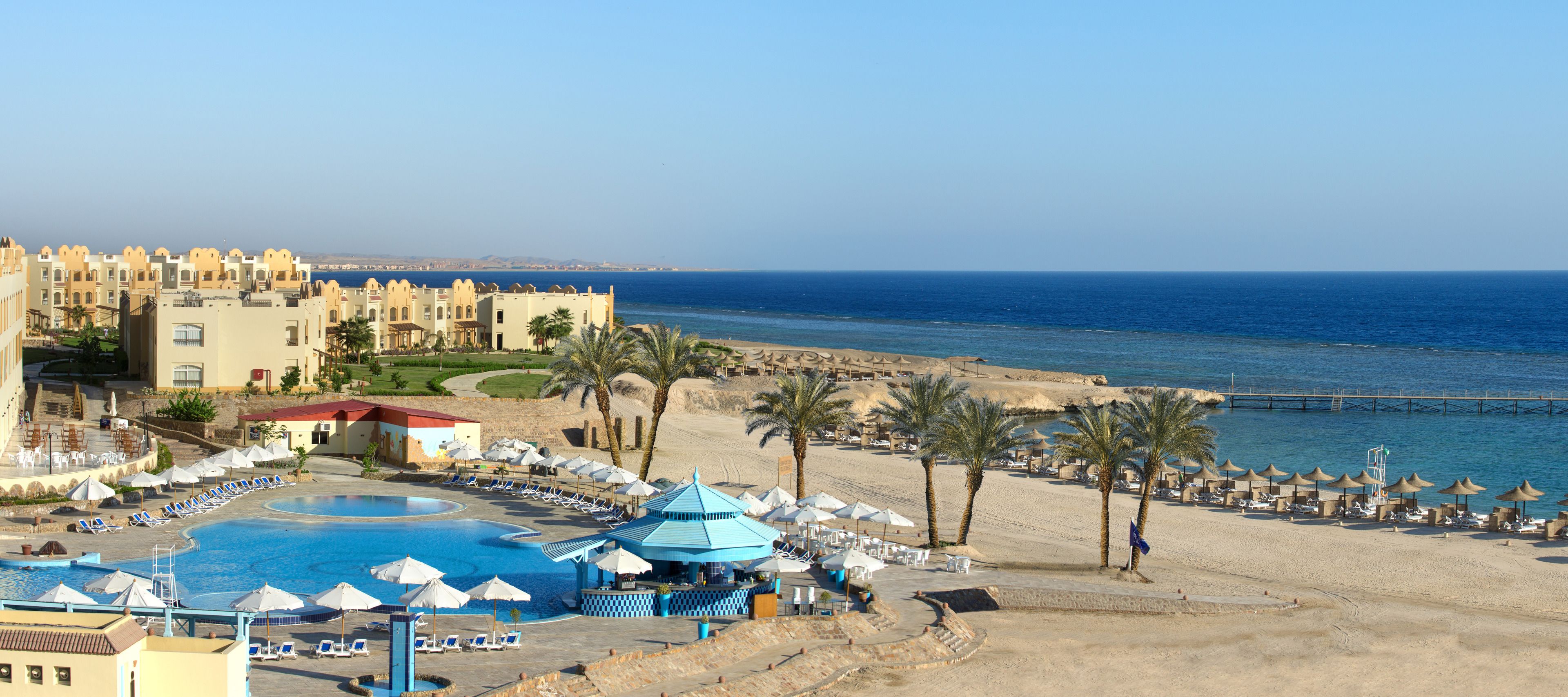 Um resort com piscina, área de praia e vista para o mar.