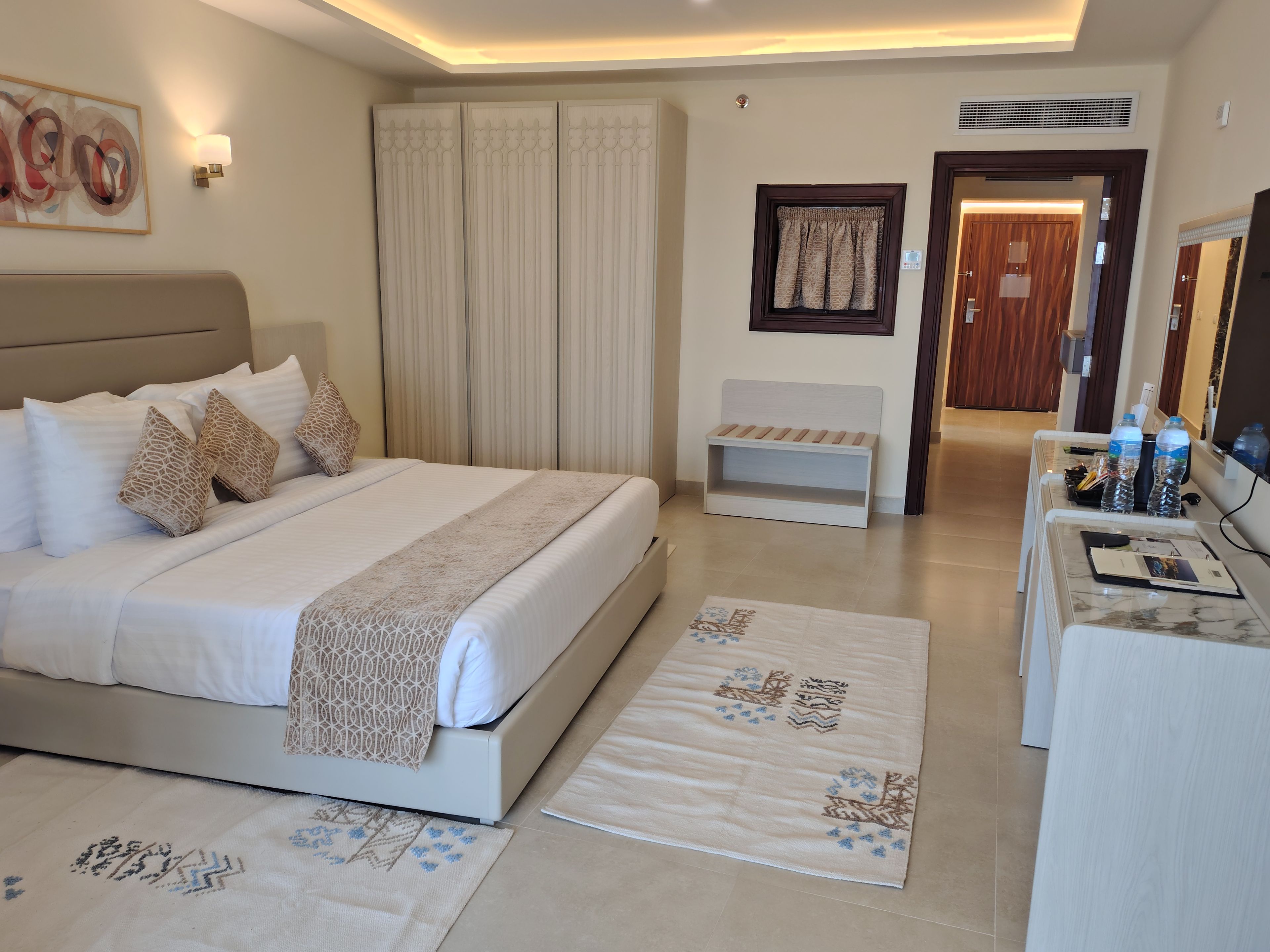A hotel room with a bed, bedside tables, a desk, and a chair.