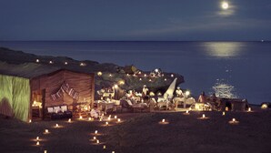 An outdoor dining area with tables and chairs, a tent, and a view of the ocean under a moonlit sky. - Concorde Moreen Beach Resort & Spa (Marsa Alam)